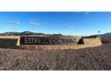 Stone entrance sign with 'Estrella Crossing' against a backdrop of mountains and blue sky at 5839 W Willow Ridge Dr, Laveen, AZ 85339