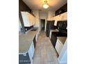 Galley kitchen featuring white cabinets, tiled floors, countertops and black appliances at 7009 E Acoma Dr # 1101, Scottsdale, AZ 85254