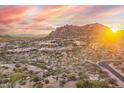 Scenic aerial view of desert homes nestled in a rocky landscape with mountains, bright sunset enhancing overall appeal at 10671 E Hedgehog Pl, Scottsdale, AZ 85262