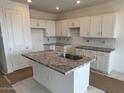 Bright kitchen features white cabinets, granite countertops and a center island with a sink at 25161 W Wayland Dr, Buckeye, AZ 85326