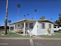 Charming home with a covered porch, desert landscaping, and mature palm trees at 4065 E University Dr # 83, Mesa, AZ 85205