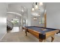 Bright game room boasts a wooden pool table beneath decorative lighting, adjacent to a staircase and open-concept living space at 4235 W Harrison St, Chandler, AZ 85226
