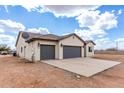 This single-story tan home boasts a spacious three-car garage, desert landscaping and a cloudy sky at 5145 E Hash Knife Draw Rd, San Tan Valley, AZ 85140