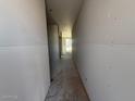Unfinished hallway showcasing its length, bare walls, and floor, offering a view towards a bright window at the end at 9613 W Parkway Dr, Tolleson, AZ 85353
