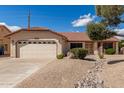 Single-story home featuring a two-car garage, xeriscaped front yard, and a welcoming front entrance at 12826 S 40Th Pl, Phoenix, AZ 85044