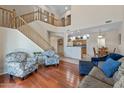 Bright, airy living room with hardwood floors, a staircase, and open access to the kitchen and dining area at 13545 W Caribbean Ln, Surprise, AZ 85379