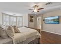 Main bedroom with a ceiling fan, wood floors, a bay window, and an ensuite bathroom, creating a relaxing retreat at 13545 W Caribbean Ln, Surprise, AZ 85379