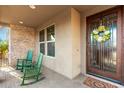 Charming front porch featuring two rocking chairs, a brick accent wall, and a decorative front door at 3110 E Cat Balue Dr, Phoenix, AZ 85050