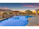 Luxurious backyard oasis features a large pool with a rock waterfall, a poolside gazebo and lounge seating at 3616 E Kachina Dr, Phoenix, AZ 85044