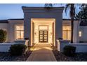 Eye-catching front entrance with a modern door framed by an illuminated portico and lush landscaping at 9440 N 57Th St, Paradise Valley, AZ 85253