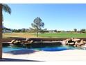 Tranquil pool area with a natural rock waterfall feature and a serene view of the adjacent golf course at 9440 N 57Th St, Paradise Valley, AZ 85253