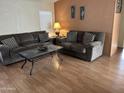 Spacious living room featuring two sofas, wood-look floors, and natural light streaming through a window at 9828 E Pueblo Ave # 67, Mesa, AZ 85208