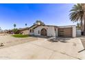 Street view of a single-story stucco home featuring an arched entryway, low-maintenance landscaping, and a detached garage at 113 W Rawhide Ave, Gilbert, AZ 85233