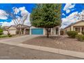 Inviting single-story home with a blue garage door, desert landscaping, and mature shade trees at 1434 W Brangus Way, San Tan Valley, AZ 85143