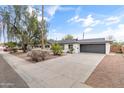 Single-story home with an attached garage and a well-manicured front yard under a blue sky at 1509 W Tuckey Ln, Phoenix, AZ 85015