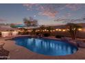 Backyard featuring a private pool with a waterfall, lounge chairs, bar area, and palm trees at 17751 W Desert View Ln, Goodyear, AZ 85338