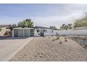 Charming single-story home featuring a modern gray garage door, xeriscaped front yard and a desert landscape at 2925 E North Ln, Phoenix, AZ 85028