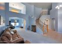 Open-concept living room featuring a winding staircase, carpeted floors, and an abundance of natural light at 6993 S Sharon Ct, Chandler, AZ 85249