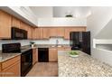 Spacious kitchen with wooden cabinets, granite countertops, and modern black appliances at 702 S Beck Ave, Tempe, AZ 85281