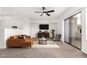 Modern living room with brown leather sofa, a ceiling fan, and sliding glass doors to a deck at 702 S Beck Ave, Tempe, AZ 85281