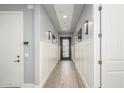 Hallway features wainscoting, wood-look tile, and modern lighting leading to an elegant entryway door at 7518 E Vista Bonita Dr, Scottsdale, AZ 85255