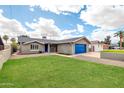 A well-maintained single-story home showcasing its manicured front lawn and blue garage door at 8637 E Jackrabbit Rd, Scottsdale, AZ 85250