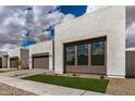 Contemporary home featuring a three car garage and a well-manicured lawn at 10308 E Utah Ave, Mesa, AZ 85212
