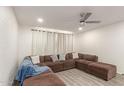 Comfortable living room featuring a large sectional sofa, neutral decor, and modern ceiling fan, ideal for relaxation at 1253 E Avila Ave, Casa Grande, AZ 85122
