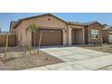A view of the home's front exterior showcasing the driveway, garage, desert landscaping, and covered front porch at 15053 W Gray Fox Trl, Surprise, AZ 85387