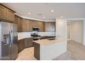 Modern kitchen with stainless steel refrigerator, island with sink, and pendant lighting at 15818 W Kendall St, Goodyear, AZ 85338