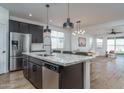 Modern kitchen boasts granite countertops, stainless steel appliances, and stylish pendant lighting above the island at 17826 W Monte Lindo Ln, Surprise, AZ 85387