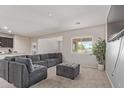 Inviting living area featuring an oversized gray sofa, large window, and stylish furnishings at 18658 N Desert Willow Dr, Maricopa, AZ 85138