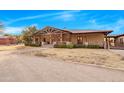 Stunning ranch-style home boasts a covered porch with stone pillars and manicured landscaping at 51238 N Pinal Ranch Rd, Miami, AZ 85539