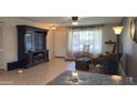Cozy living room with neutral walls, large window with patterned curtains, and entertainment center at 9814 W Shasta Dr, Sun City, AZ 85351