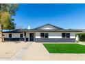 Beautiful single-story home featuring gravel landscaping, lush grass, and a stylish black and white color scheme at 1504 E Jasmine St, Mesa, AZ 85203