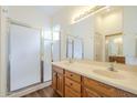 Bright bathroom with double sinks, wood cabinets, and a glass-enclosed shower, and wood-look floors at 18250 N Coconino Dr, Surprise, AZ 85374