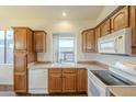 Kitchen featuring wood cabinets, white appliances, and a window over the sink, with tile countertops at 18250 N Coconino Dr, Surprise, AZ 85374