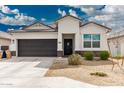 Well-maintained single-story home with a dark grey two-car garage and easy desert landscaping at 24029 W Zak Rd, Buckeye, AZ 85326