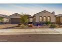 Charming single-story home featuring a meticulously landscaped front yard with desert plants and unique stone accents at 26231 W Maple Dr, Buckeye, AZ 85396