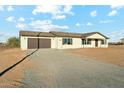 Single-story home with a two-car garage and long gravel driveway, set against a blue sky with scattered clouds at 2744 S 357Th Dr, Tonopah, AZ 85354