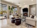 Cozy living room with a marble fireplace, large windows overlooking the pool, and comfortable seating at 27728 N 68Th Pl, Scottsdale, AZ 85266