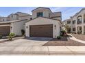 A two-car garage with a brown garage door, exterior lights, landscaping, and long driveway on a sunny day at 14200 W Village Pkwy # 107, Litchfield Park, AZ 85340