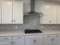 Close up of the kitchen with white cabinets, tile backsplash and a stainless steel range hood at 16954 W Molly Ln, Surprise, AZ 85387