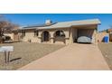 Inviting single-story home featuring a covered carport, stone landscaping, and a well-maintained driveway at 4366 E Burgess Ln, Phoenix, AZ 85042