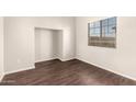 A bright, empty bedroom featuring wood-look floors, a closet nook, and a window with a view at 4675 E Olney Ave, Gilbert, AZ 85234