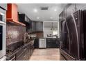 Modern kitchen with sleek black cabinetry, stainless steel appliances, and a stylish backsplash at 5324 W Carol Ave, Glendale, AZ 85302