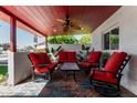 Relaxing outdoor patio featuring comfortable red seating, a ceiling fan, and lush greenery at 5324 W Carol Ave, Glendale, AZ 85302