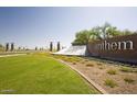 Landscaped entry to Anthem by Del Webb with manicured lawn and clear blue sky at 7854 W Mockingbird Way, Florence, AZ 85132