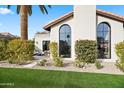 Lovely home showcasing arched windows, landscaped greenery, and an outdoor seating area at 8206 E Del Camino Dr, Scottsdale, AZ 85258