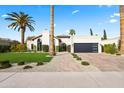 Beautiful home featuring a manicured lawn, palm trees, and a brick pathway leading to the entrance at 8206 E Del Camino Dr, Scottsdale, AZ 85258